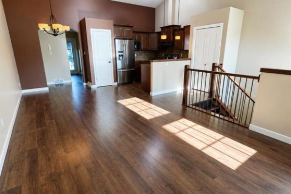 Open concept living and dining area with dark wood floors. - 89 Lynx Road N, Lethbridge