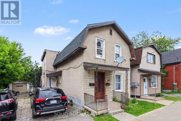 Exterior view of a duplex-style home with tan siding and two entrance doors. - 89 Marier Avenue, Ottawa