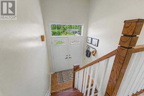 Front view of a brick house with two garage doors, a central entrance, and green grass. - 89 Metro Road N, Georgina