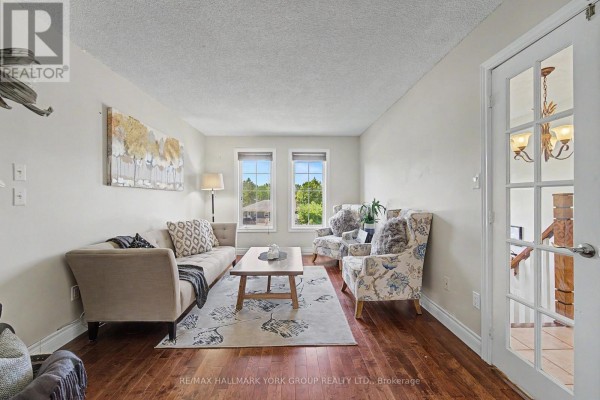 View from above of an entryway with white double doors, a staircase with wooden railing, and tile flooring. - 89 Metro Road N, Georgina