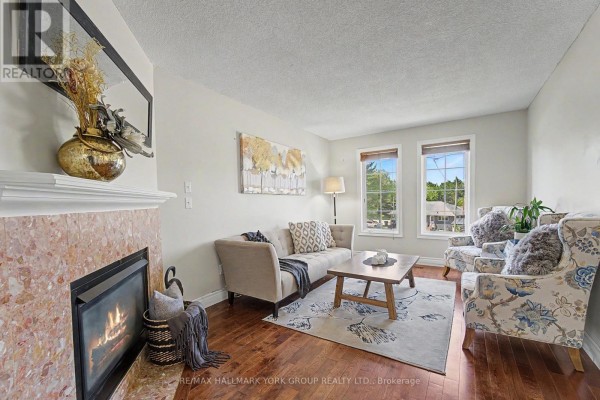 Living room with hardwood floors, a sofa, two armchairs, a coffee table, and a fireplace visible through a doorway. - 89 Metro Road N, Georgina