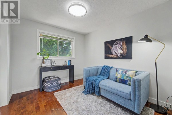 Living room with hardwood floors, a sofa, two armchairs, a coffee table, and a fireplace on the left wall. - 89 Metro Road N, Georgina