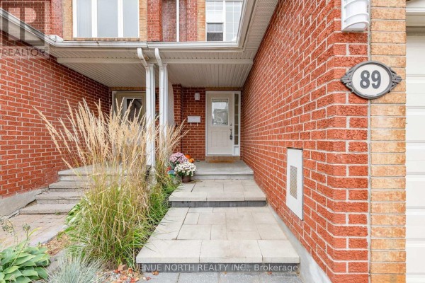 Close-up of the townhouse entrance with stairs, walkway, and decorative grass. - 89 Silverlace Private, Ottawa