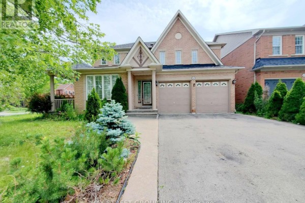 A wide shot of the front of a brick house with a paved driveway and landscaping. - 89 Skywood Drive, Richmond Hill