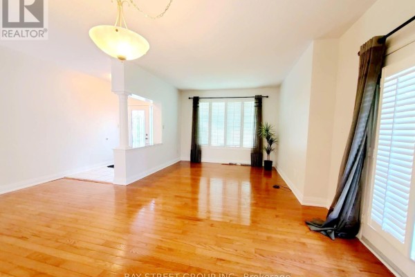 Interior view of a spacious living and dining area with hardwood floors and large windows. - 89 Skywood Drive, Richmond Hill