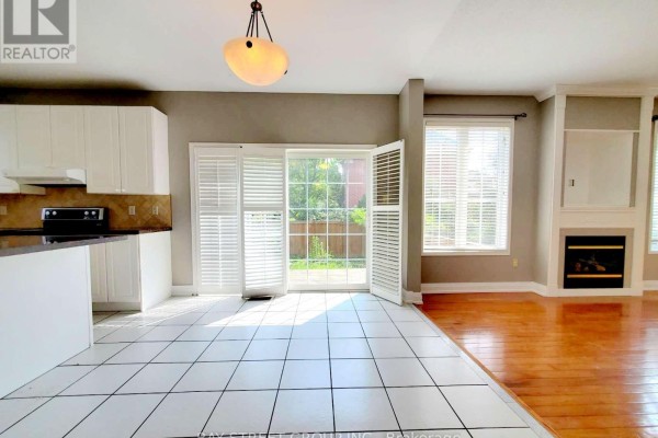 A view of the kitchen island and adjacent living area with a fireplace and patio doors. - 89 Skywood Drive, Richmond Hill