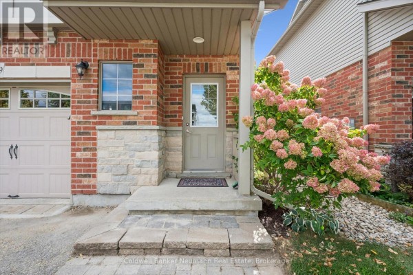 Close-up view of the front entrance steps and door, with flowering shrubs to the right. - 89 Washburn Drive, Guelph