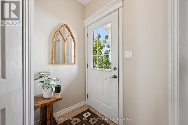 Interior view of the front entrance hallway showing a white door and wooden mirror. - 89 Washburn Drive, Guelph