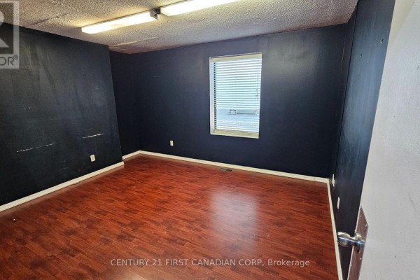 Small empty room with dark blue walls and a wood-look floor. - 89 Wharncliffe Road N, London North