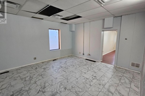 Empty room with light blue walls, marbled tile floor, and ceiling tiles. - 89 Wharncliffe Road N, London North