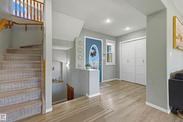 Interior view of a foyer and staircase with light grey walls and beige carpeted steps. - 8903 176 Av Nw, Edmonton