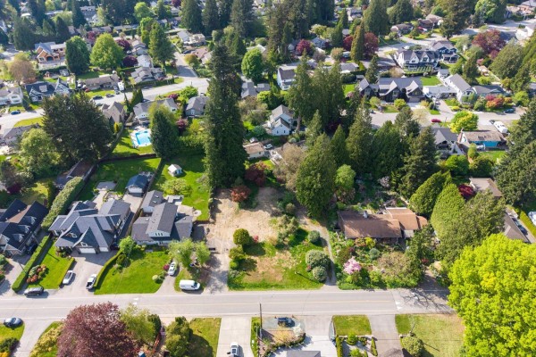 Aerial view of a neighborhood showing a vacant lot surrounded by houses and trees. - 8917 Nash Street, Langley