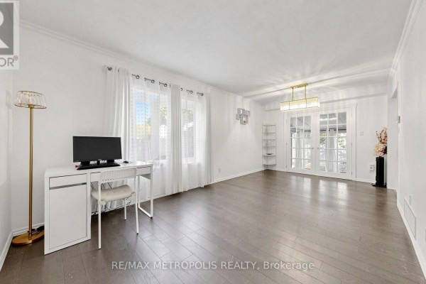 Spacious living room with white walls, light wood floors, and double glass doors. - 892 Gentry Crescent, Oshawa