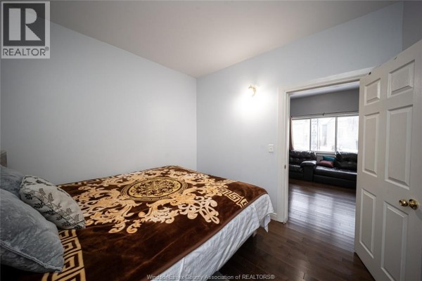 Bedroom with ornate blanket and open doorway to living room with leather sofas - 894 University Avenue Windsor