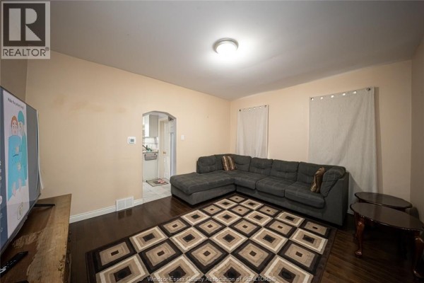 Sectional sofa, rug, and TV in living room with archway to kitchen - 894 University Avenue Windsor