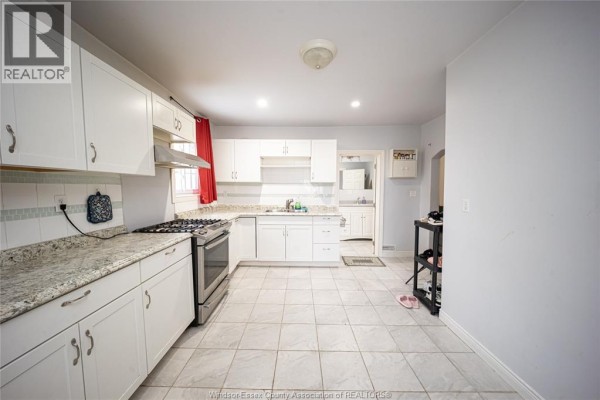 Kitchen with white cabinets, granite countertops, gas range, and tile flooring - 894 University Avenue Windsor