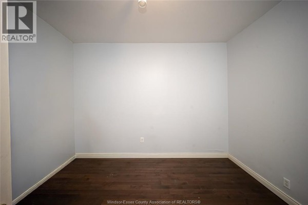 Empty room with hardwood floors and light blue walls - 894 University Avenue Windsor