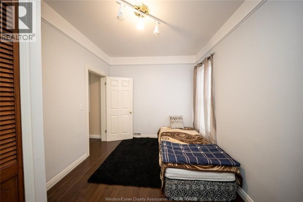 Bedroom with track lighting, hardwood floors, bed, and black rug - 894 University Avenue Windsor