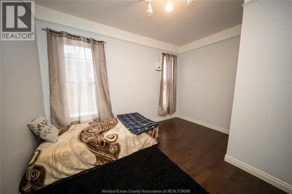 Bedroom with bed, dark wood floor, and two windows - 894 University Avenue Windsor
