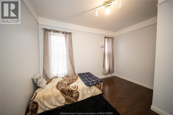 Bedroom with bed, dark hardwood floors, and two windows - 894 University Avenue Windsor