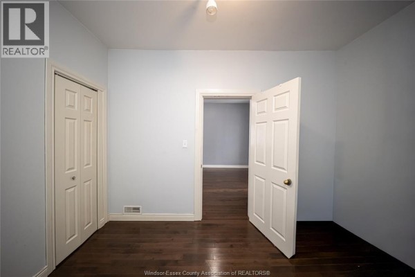 Hallway with bi-fold closet doors, dark hardwood floors, and open doorway - 894 University Avenue Windsor