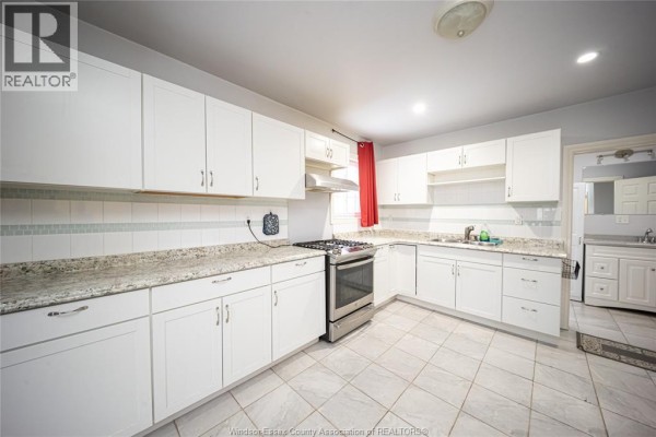 White kitchen with granite countertops, stainless steel gas range, and tile floor - 894 University Avenue Windsor