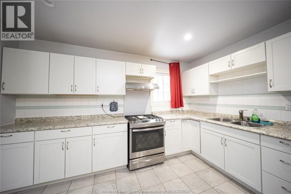 White cabinets, granite countertops, and stainless steel gas range in kitchen - 894 University Avenue Windsor