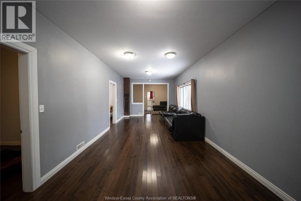Living room with hardwood floors, brick fireplace, and black sofa - 894 University Avenue Windsor