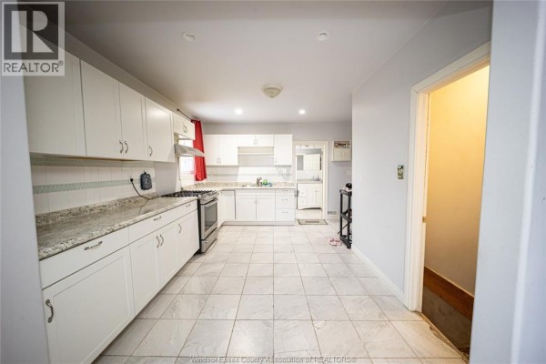 U-shaped kitchen with white cabinets, granite counters, stainless steel gas range, and tile floor - 894 University Avenue Windsor