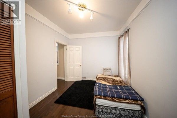 Bedroom with wood floors, dark rug, bed, and track lighting - 894 University Avenue Windsor
