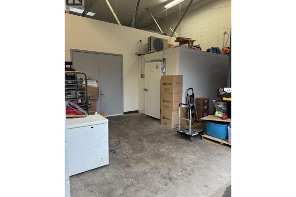 Interior view of a commercial space with a walk-in freezer, storage boxes, and a concrete floor. - 8940 Douglas Street, Richmond