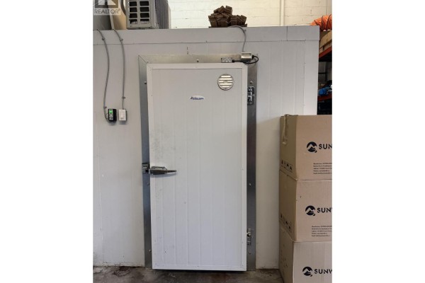 Close-up of a large white walk-in freezer door with stainless steel trim and a ventilation grate. - 8940 Douglas Street, Richmond