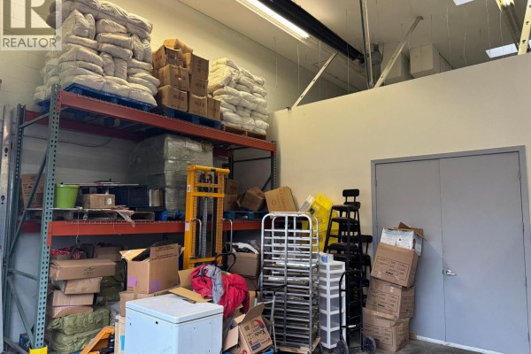 Commercial storage area with tall metal shelving units, pallets of goods, a yellow forklift, and various boxes. - 8940 Douglas Street, Richmond