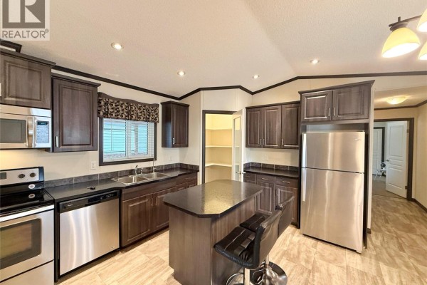 Living room with patterned recliners, a sofa, and a television. - 8945 Highway 97 N Highway Unit# 5, Kelowna