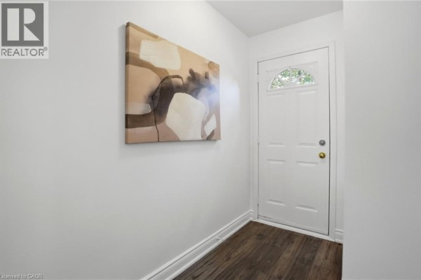 Interior view of a white entryway with a glass-paned door and abstract wall art. - 895 Maple Avenue Unit# 407, Burlington