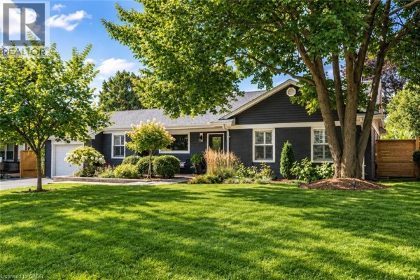 Side view of dark grey bungalow with white trim, manicured lawn, trees, and landscaping. - 896 Eagle Drive, Burlington