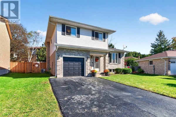 Driveway and front lawn of the house with trees and neighboring garages. - 896 Mona Drive, Kingston