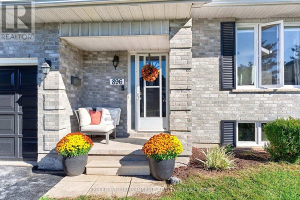 Close-up of the house entrance with a white door, two large potted plants, and seating. - 896 Mona Drive, Kingston