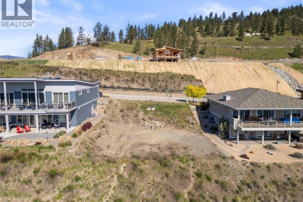 Empty lot with a view of a lake, homes, and construction on a hillside. - 8972 Tavistock Road, Vernon