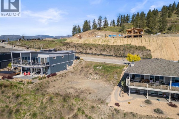 Empty lot situated on a hillside overlooking a lake, with surrounding homes. - 8972 Tavistock Road, Vernon