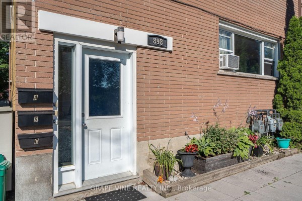 Close-up of the front entrance with mailboxes and potted plants on the exterior brick wall. - 898 Watson Avenue, Ottawa