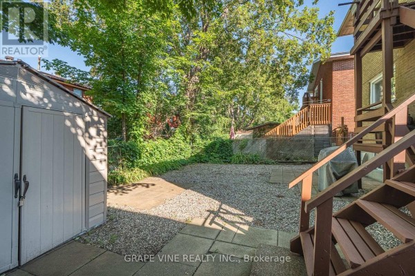 Backyard view with a shed, gravel patio, and wooden stairs leading to a deck. - 898 Watson Avenue, Ottawa