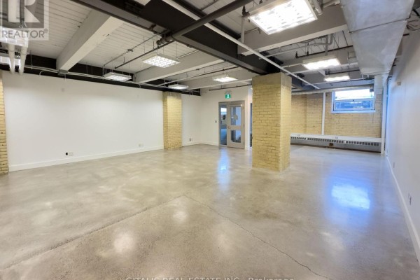 Wide view of an open commercial space featuring white walls and concrete floors. - 8a - 219 Dufferin Street, Toronto