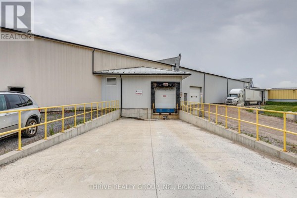 Wide gravel lot in front of the commercial building with parked vehicles. - 8a - 516 John Street N, Aylmer