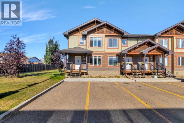 Front exterior of townhouses with asphalt parking in foreground and grassy area to the left. - 9, 4738 13 Street, Lloydminster