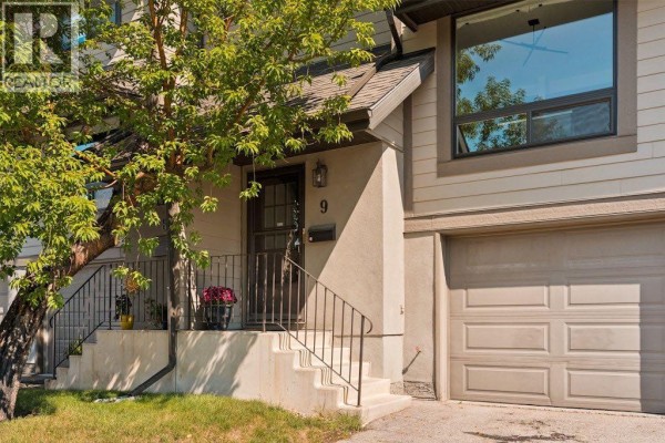 Close-up of townhouse entrance with steps, railings, a dark front door, and garage to the right. - 9, 5019 46 Avenue Sw, Calgary