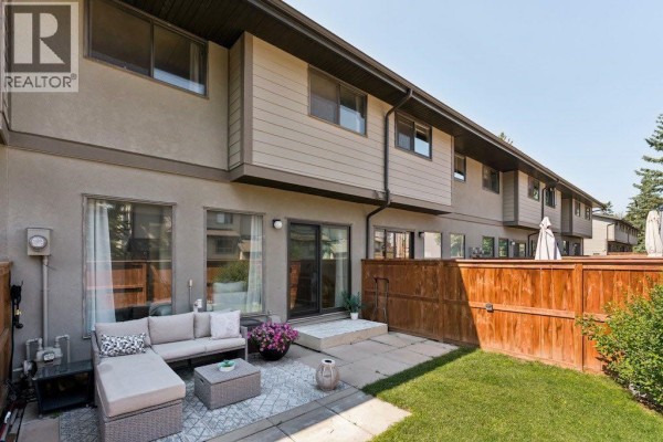 Backyard patio with outdoor furniture, grassy area, and wooden fence. - 9, 5019 46 Avenue Sw, Calgary