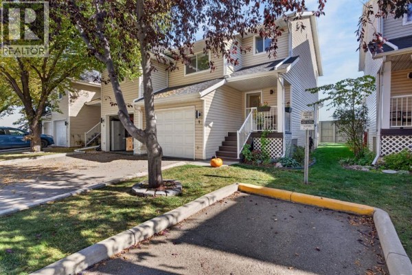 Exterior view of townhouse with driveway, garage, and front entrance. - 9, 567 Edmonton Trail Ne, Airdrie