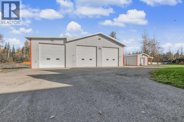 Three-bay metal workshop with large garage doors and a smaller attached shed, surrounded by trees. - 9, 710072 40 Highway, Rural Grande Prairie No  1, County Of