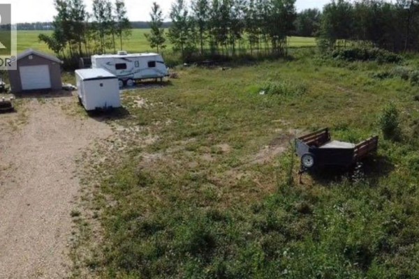 Wide view of a cleared lot with a shed, trailer, and utility building. - 9, 842052 Range Road 241, Rural Northern Lights, County Of